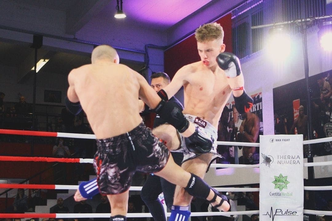 Semyon competing in the ring, landing a knee strike.